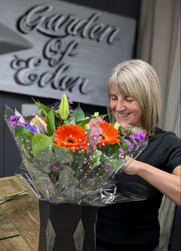 Garden of Eden Florist hand arranging florist choice bouquet with vibrant coloured flowers